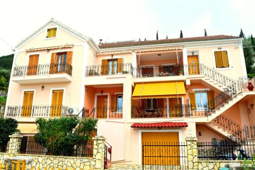 an apartment building with yellow doors and balconies at Korona Apartments in Vathi, Ithaka