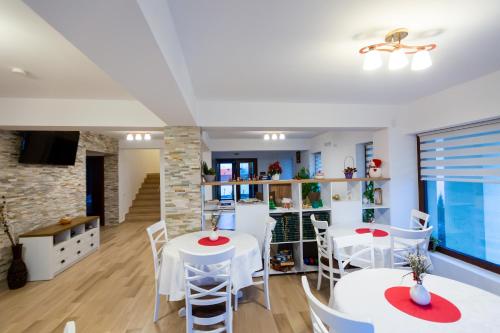 une salle à manger avec des tables et des chaises blanches dans l'établissement Pensiunea Mateo, à Buzău