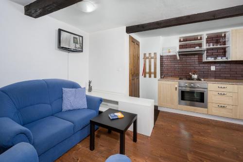 a living room with a blue couch and a kitchen at Penzion Pod Sudem in Lázně Libverda