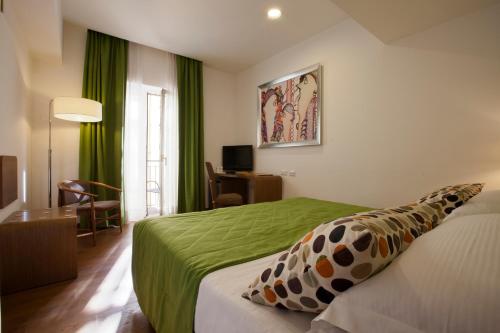 a hotel room with a bed with a green blanket at Hotel Plaza in Sorrento
