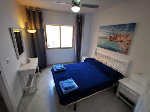 um pequeno quarto com uma cama azul e uma janela em Cosy apartment Arenal Bol em Calpe