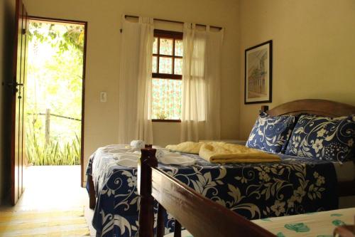 a bedroom with a bed with blue and white sheets at Pousada Ponte Branca in Paraty
