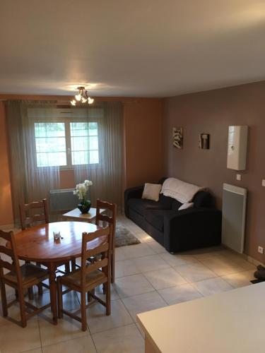 uma sala de estar com uma mesa e um sofá em La Maisonnette Dintevilloise em Dinteville