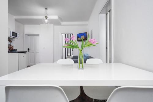 a white dining room table with pink flowers in a vase at Penzion Pod Sudem in Lázně Libverda