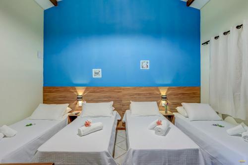 fila de camas en una habitación con una pared azul en i9 Bem Bela Pousada, en Itacaré