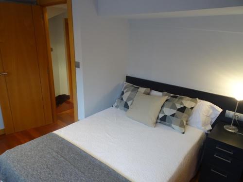 a bedroom with a bed with pillows and a lamp at Lamerako Etxie - La Casa del Parque - Park s Home in Bermeo