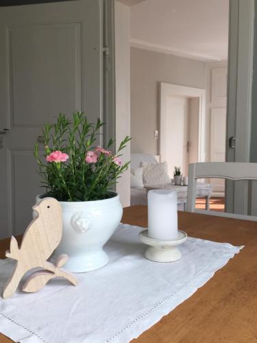 a table with a white vase with flowers and a candle at Appartment Entegast - Edles Landhausflair zum Geniessen in Schopfheim