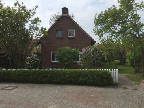 a red brick house with a white fence in front at Ferienhaus Schonerweg 9 in Norddeich in Norddeich