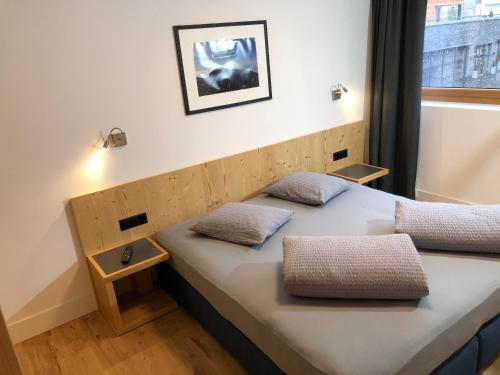 a bed in a room with two pillows on it at Catrina Apartments in Disentis