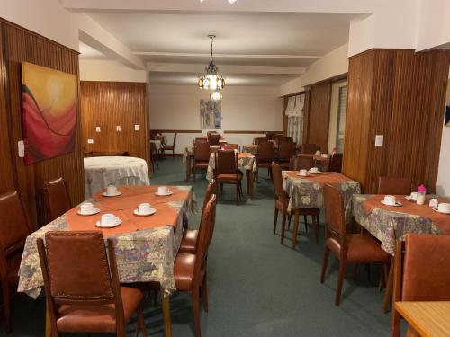 una sala da pranzo con tavoli e sedie e un lampadario di Hotel La Golondrina a Pinamar