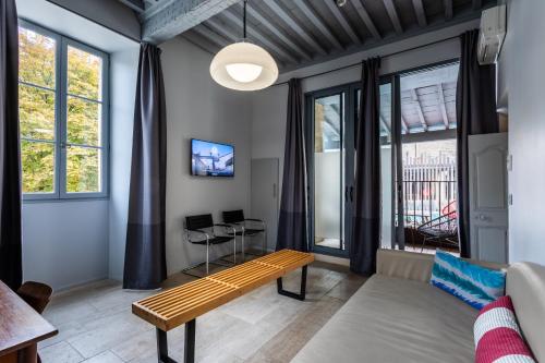a living room with a bench and windows at Boutique Hôtel Entraigues in Uzès