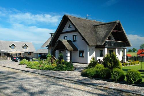 a large white house with a thatched roof at Pod Strzechą in Darłowo