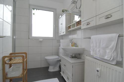 a white bathroom with a toilet and a sink at Kleine Ferienwohnung Bederkesa in Bad Bederkesa