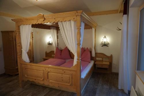 a bedroom with a wooden canopy bed with pink pillows at Ferienwohnung Almsuite Fritz in Wald im Pinzgau