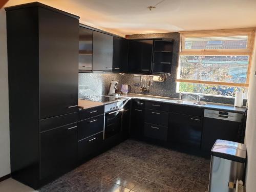a kitchen with black cabinets and a sink at Lake house 21 relax accommodation iR Sauna in Warmond