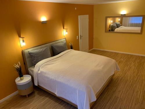 ein Schlafzimmer mit einem großen weißen Bett und einem Spiegel in der Unterkunft Moderne Ferienwohnung nahe SWR und Golfplatz in Baden-Baden