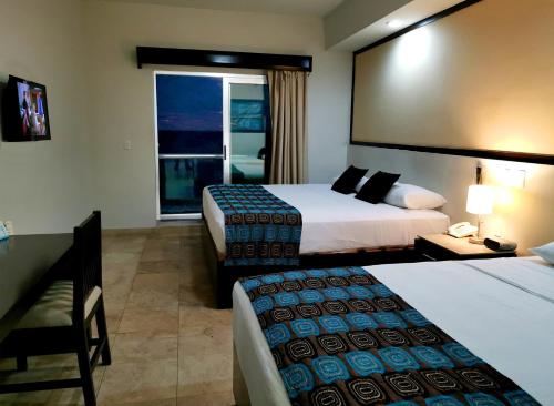 a hotel room with two beds and a window at Coral Island Beach View Hotel in Mazatlán