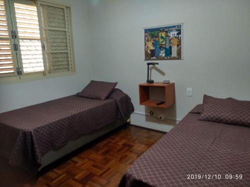 a bedroom with two beds and a desk with a lamp at CASA 230 - Guest House in Piracicaba