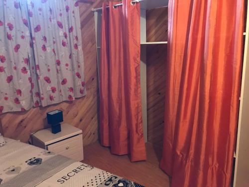 Appartement du Chalet في Koungou: غرفة نوم مع ستائر برتقالية وسرير