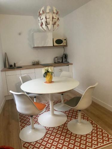 a white table and four chairs in a kitchen at Logement Cosy à 5mn du Futuroscope in Jaunay-Marigny