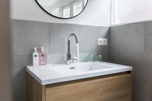 a bathroom with a white sink and a mirror at Maison Bon Apartments in Den Bosch