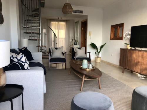 ein Wohnzimmer mit einem weißen Sofa und einem Tisch in der Unterkunft Luxurious duplex penthouse with golf and sea views in Benalmádena