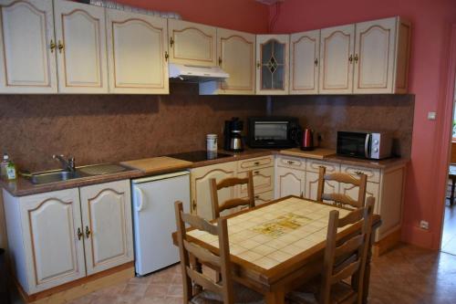 une cuisine avec des armoires blanches et une table et des chaises dans l'établissement la maison aux jardins, à Charleville-Mézières