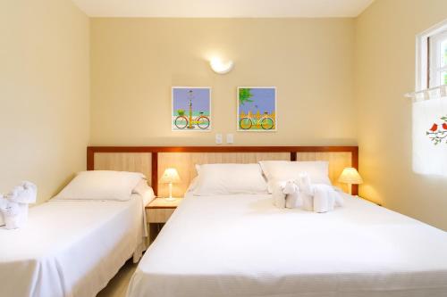 two beds in a room with white sheets at Pousada Don Diego in Ubatuba