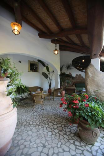 a living room with some plants and flowers at Hotel Poseidonia in Àrbatax