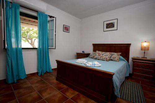 1 dormitorio con 1 cama con cortinas azules y ventana en Tapada da Beirã, en Marvão