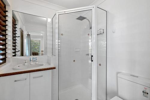 ein weißes Bad mit einer Dusche und einem Waschbecken in der Unterkunft Shifting Sands in Point Lookout