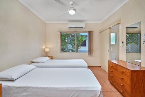 a bedroom with two beds and a dresser and a window at Royal Palm Villas in Cairns