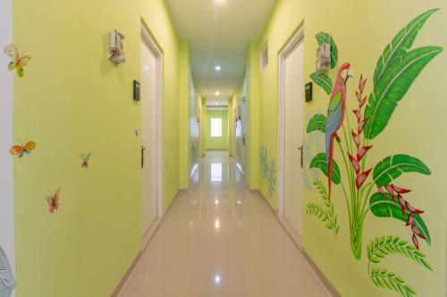 a hallway with yellow walls with plants and bugs on the walls at Omah Manis in Yogyakarta