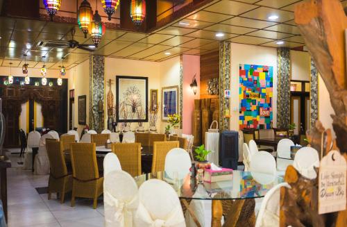 a restaurant with white chairs and a glass table at Lost Paradise Resort in Batu Ferringhi