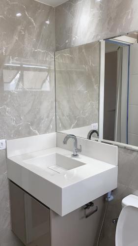 a bathroom with a white sink and a mirror at Flat na Barra - Vista para o Mar in Rio de Janeiro