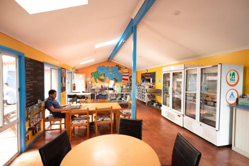 a man sitting at a table in a restaurant at Ozzie Pozzie Backpackers - Port Macquarie YHA in Port Macquarie