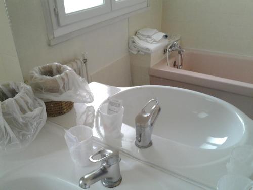 a white bathroom with a sink and a mirror at Hotel De Rouen in Louviers