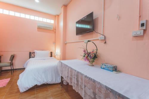 a room with two beds and a tv on the wall at Gaiwandhanat Homestay in Bangkok
