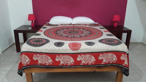 a bed that has a red blanket on it at Villas Tortugas Akumal in Akumal