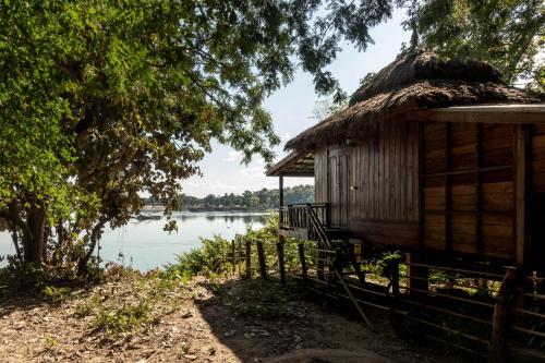 une maison au toit de chaume à côté d'un lac dans l'établissement Pomelo Restaurant and Guesthouse's Fishermen Bungalow & A Tammarine Bungalow River Front, à Ban Khon