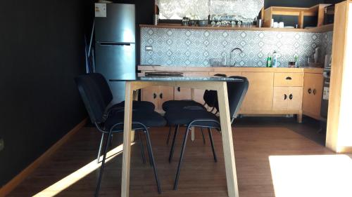 a kitchen with a table and two stools at Valdivia, Cabañas camino a Niebla in Valdivia