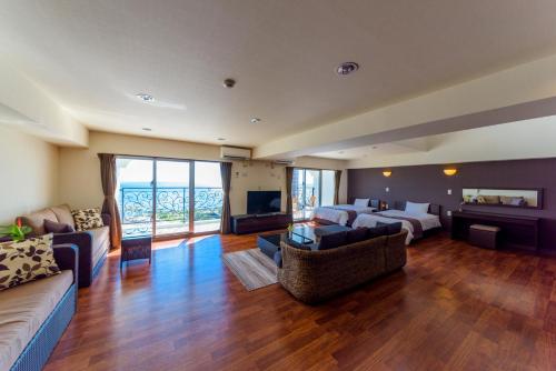 ein großes Wohnzimmer mit einem Bett und einem Sofa in der Unterkunft Condominium Hotel Monpa in Chatan