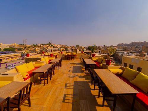 une rangée de tables et de bancs sur un toit dans l'établissement Hotel Pleasant Haveli - Only Adults, à Jaisalmer