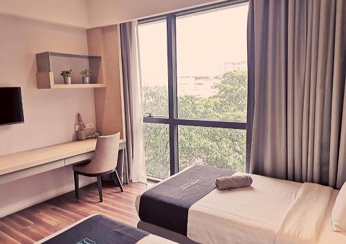 a hotel room with a bed and a desk and a window at D'majestic Place By Homes Asian 03 in Kuala Lumpur