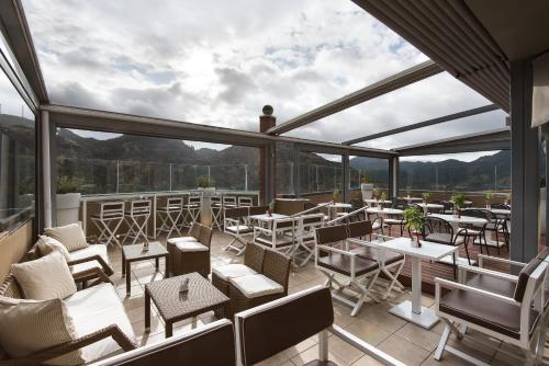 a patio with tables and chairs on a balcony at Lagadia 4 Seasons Hotel in Lagadia