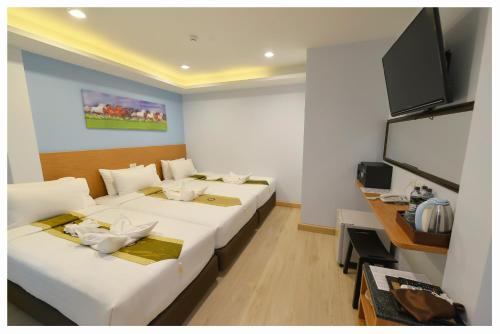 4M Pratunam Hotel في بانكوك: غرفة بثلاث اسرة وتلفزيون بشاشة مسطحة