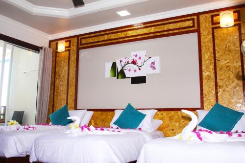 three beds in a room with a large screen at Athens View Hotel in Guraidhoo