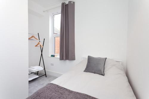 a white bedroom with a bed and a window at Clarendon in Leicester