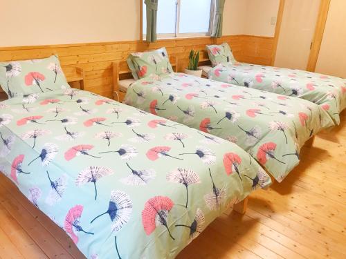 a bedroom with two beds with dandelions on them at HIBARI GUESTHOUSE in Sendai