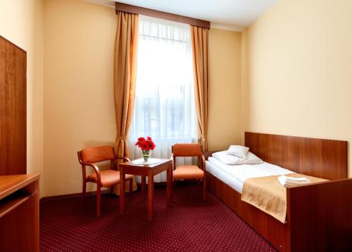 a hotel room with a bed and a table and chairs at Soplicowo in Krynica Zdrój